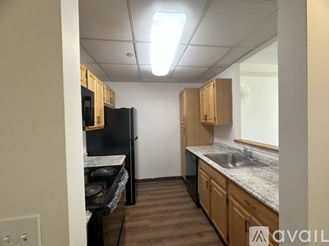 A kitchen with wooden cabinets and a black fridge.