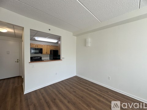 A room with a wooden floor and a white wall with a mirror on it.
