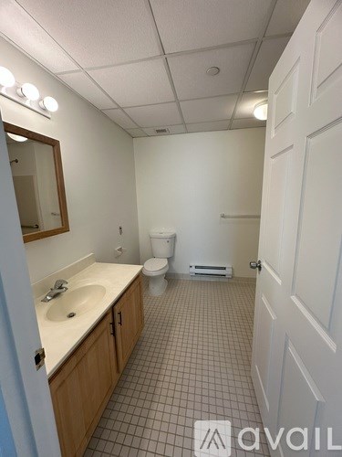 A bathroom with a toilet, sink, and mirror.