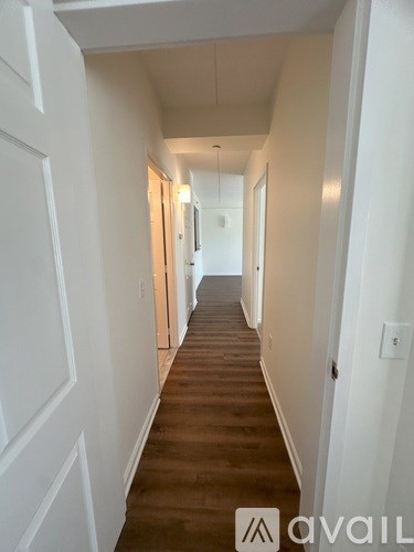 A long hallway with white walls and wood flooring.