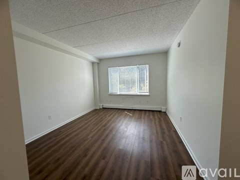 A room with wooden flooring and a window with blinds.