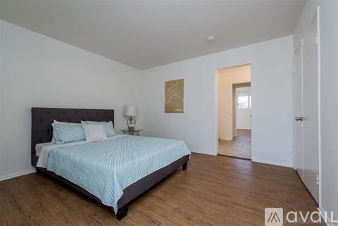 A bedroom with a bed, lamp, and artwork on the wall.