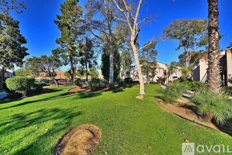 A well-maintained lawn with trees and a clear blue sky.