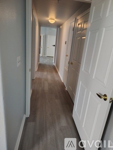 A long hallway with white doors and a wooden floor.