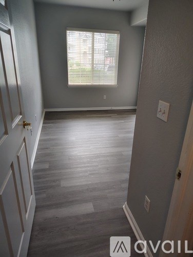 A room with wooden flooring and a window with blinds.