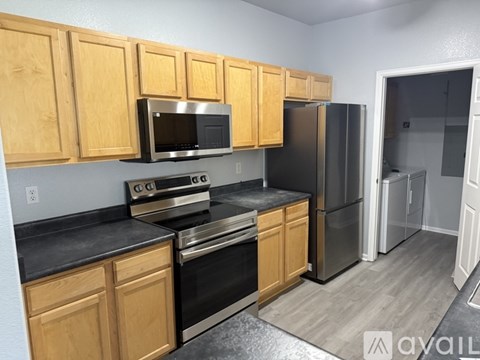 A kitchen with wooden cabinets and black countertops.