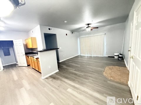 A room with a ceiling fan and a microwave on top of a cabinet.