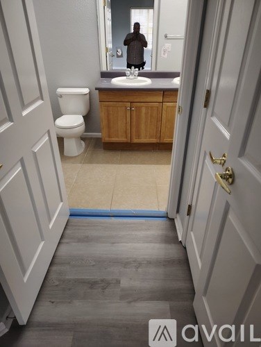 A bathroom with a toilet, sink and mirror.