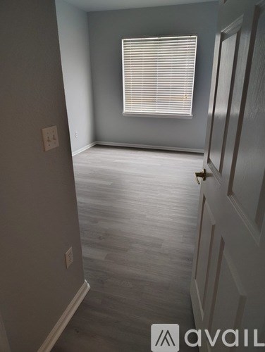 A room with a door and a window with blinds.