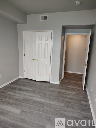 A room with a white door and wooden flooring.