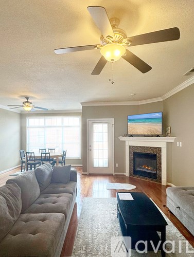 A living room with a grey couch, a fireplace, and a television.