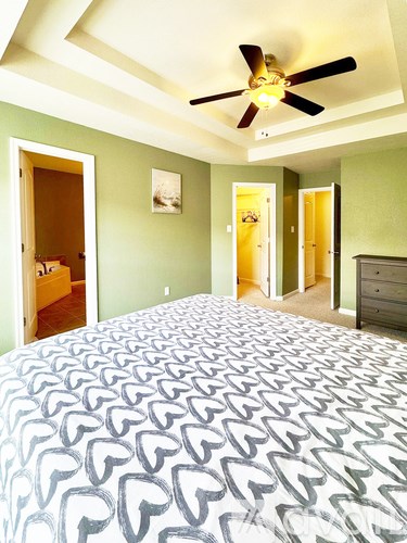 A bedroom with a large bed and a ceiling fan.