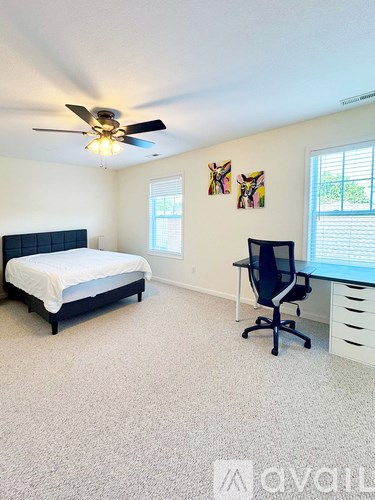 A bedroom with a bed, desk, and ceiling fan.