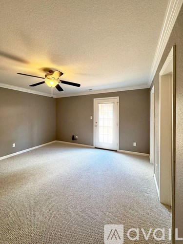 A room with a carpeted floor and a ceiling fan.
