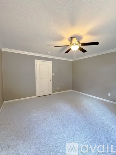 A room with a ceiling fan and a door.