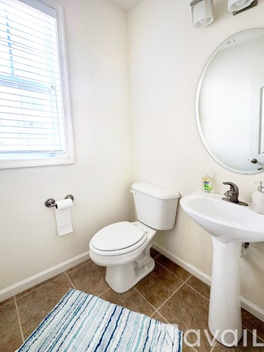 A bathroom with a toilet, sink, and window.