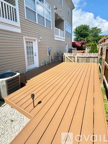 A wooden deck with a table and chairs is in front of a house.