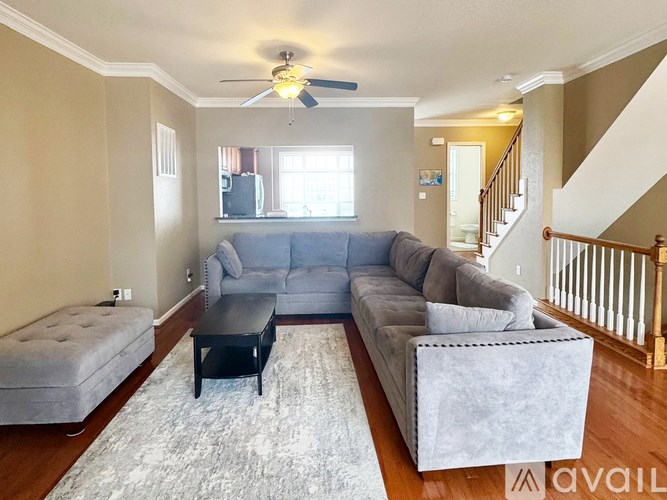 A living room with a grey couch, ottoman, and a black coffee table.