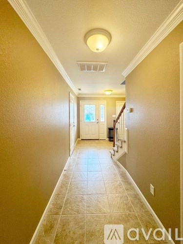 A hallway with tiled flooring and a white door at the end.