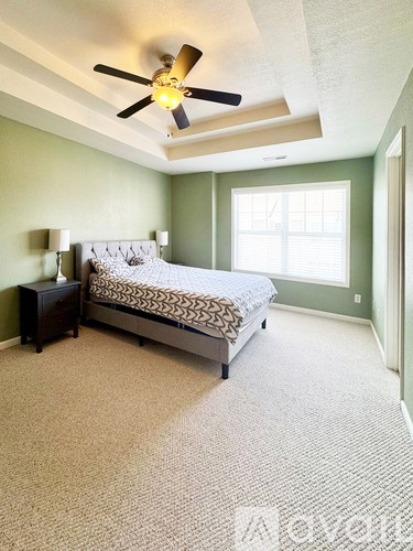 A bedroom with a bed, nightstand, and ceiling fan.