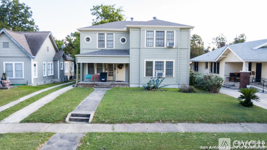 A house with a grey front yard and a small tree.