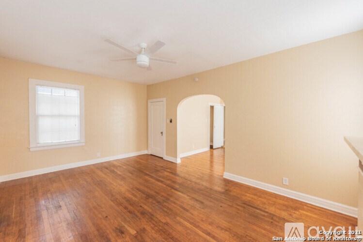 Empty room with wood flooring and a ceiling fan.