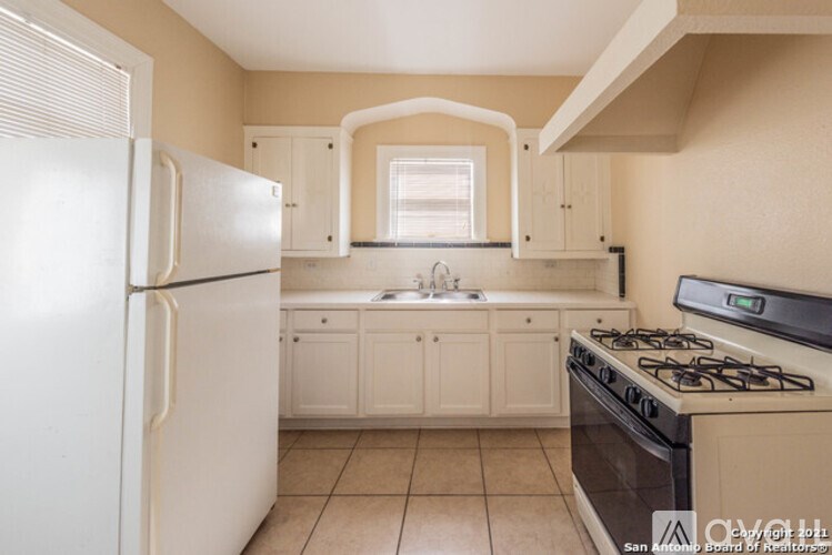 A kitchen with a white refrigerator and a black stove top oven.