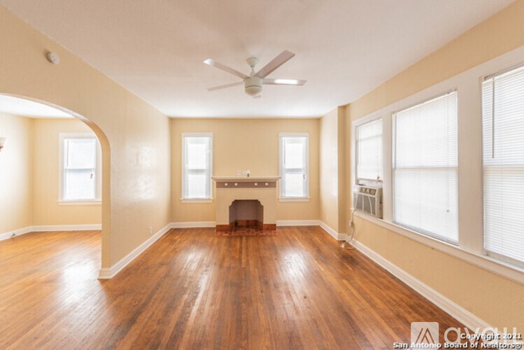 A spacious room with wood flooring and a fireplace.
