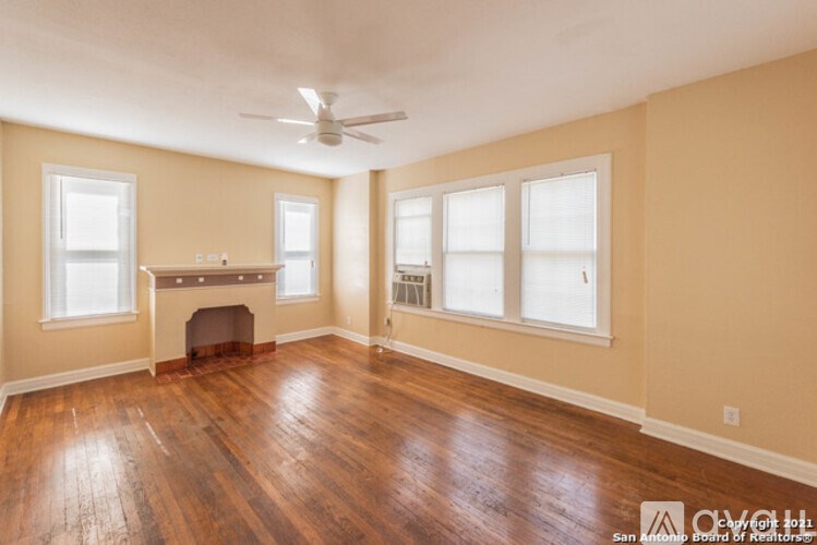 A spacious room with wood flooring and a fireplace.
