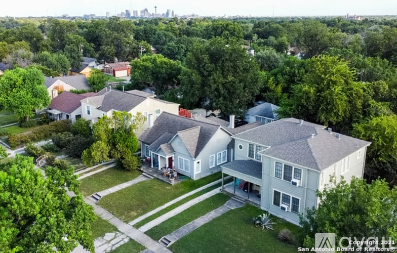 A bird's eye view of a suburban neighborhood with a large house in the foreground.