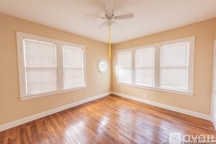 A room with a ceiling fan and three windows.