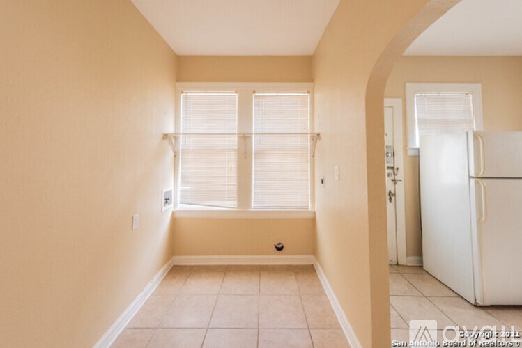 A room with beige walls and a white refrigerator.