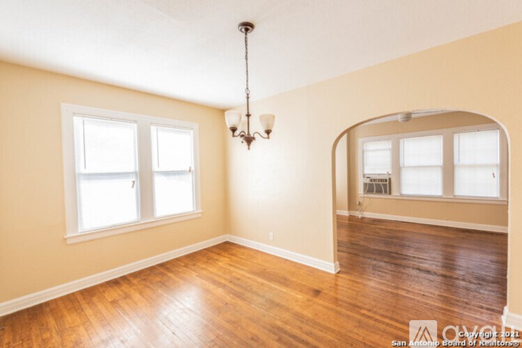 A room with wooden floors and a chandelier hanging from the ceiling.