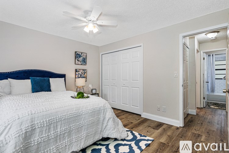 A bedroom with a white bed and a ceiling fan.