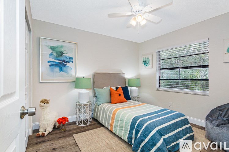 A bedroom with a bed, a ceiling fan, and a painting on the wall.