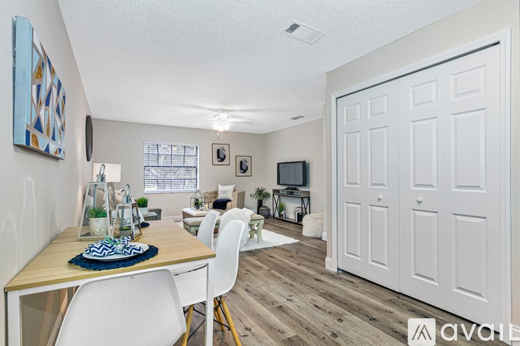 A dining room with a wooden table and chairs, a television, and a white door leading to another room.