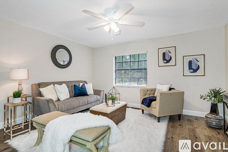 A living room with a grey couch, a white rug, and a ceiling fan.