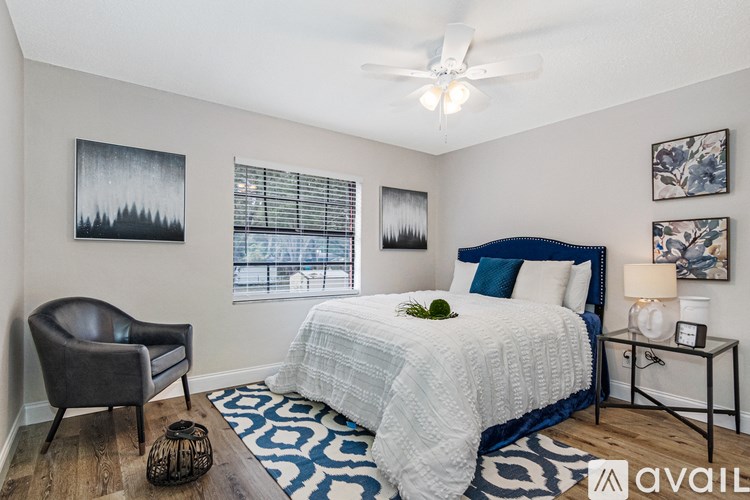 A bedroom with a bed, chair, and pictures on the wall.