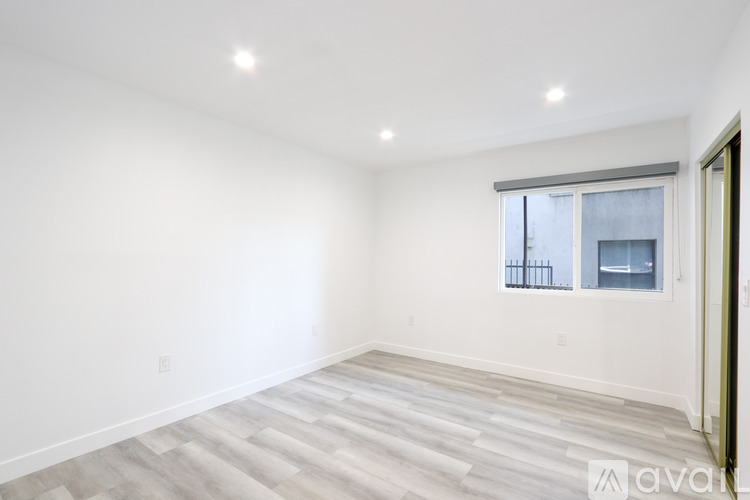 A spacious room with a window and a wooden floor.