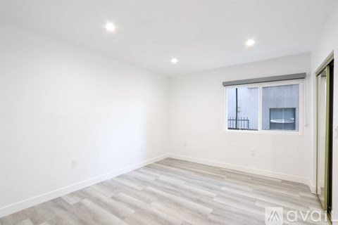 A spacious room with a window and a wooden floor.