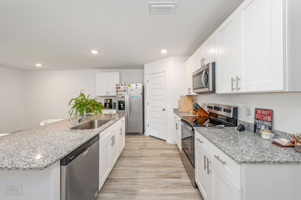 A kitchen with white cabinets and granite countertops.