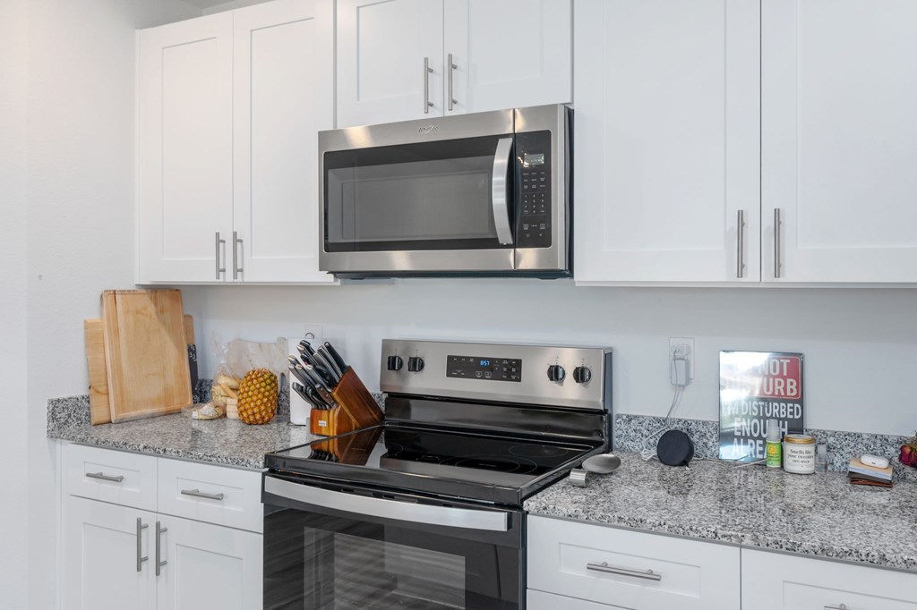 A kitchen with a stove, microwave, and cabinets.