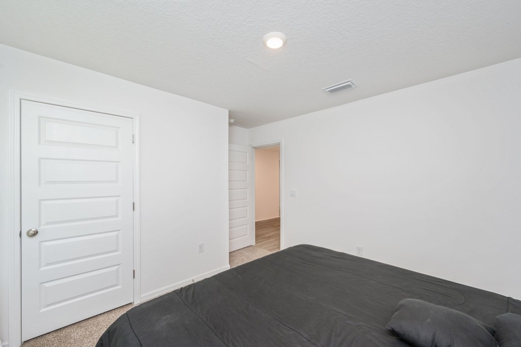 A bedroom with a bed, a door, and a window.