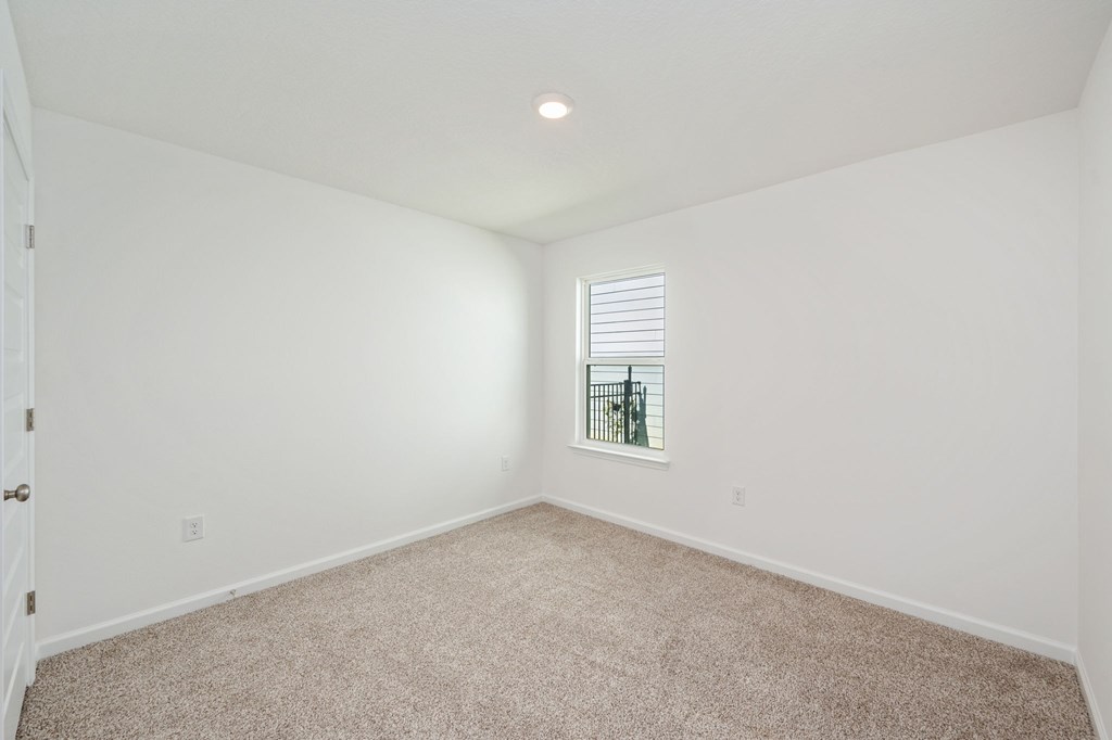 A room with a carpeted floor and a window with blinds.