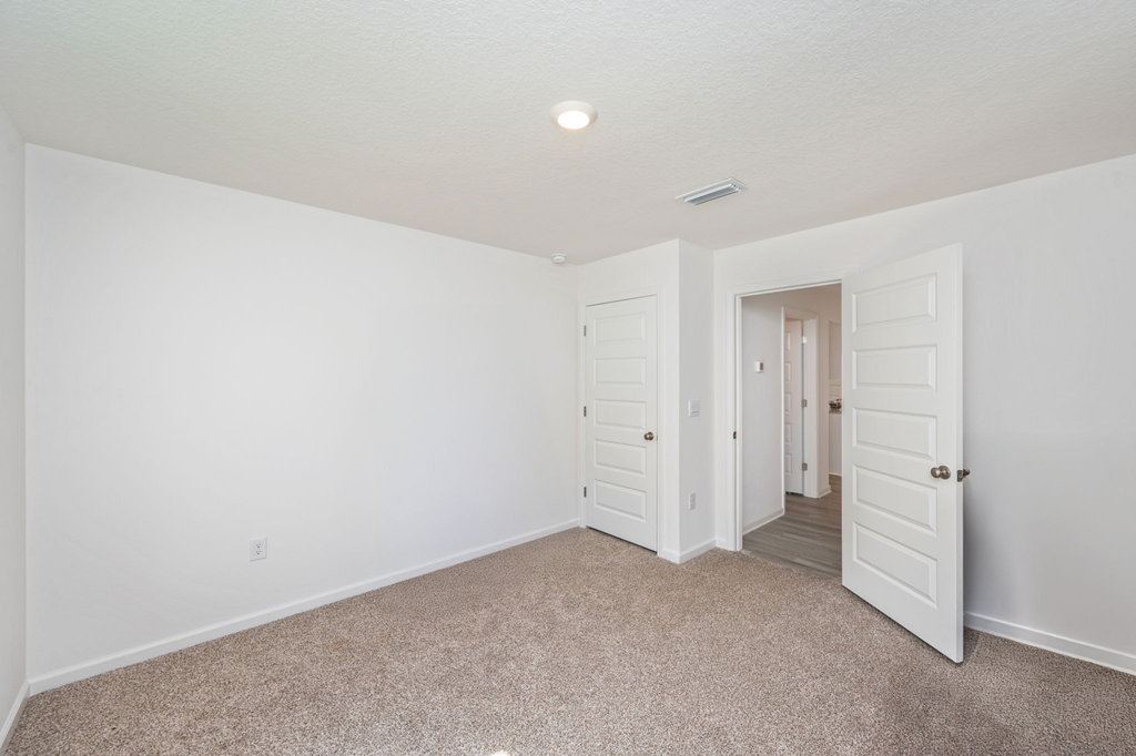 A white room with a carpeted floor and two doors.