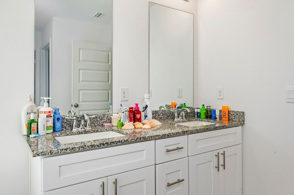 A bathroom with a white vanity and a mirror above the sink.