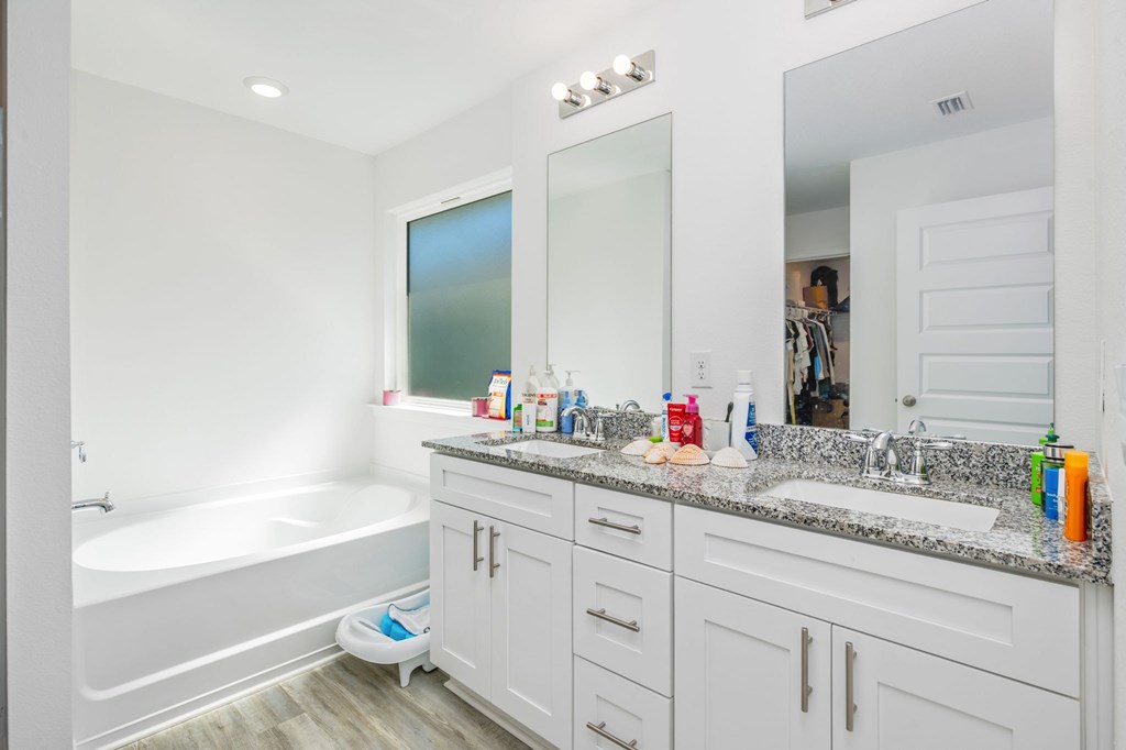 A bathroom with a white tub, sink, and vanity.