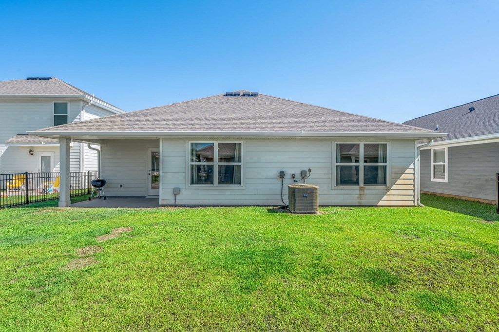 A white house with a brown roof and a green lawn in front.