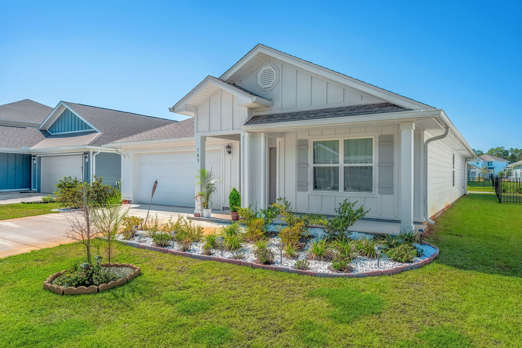 A house with a well-maintained lawn and a small garden in front.