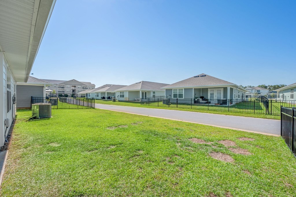 A row of houses with a fence and green grass in front.